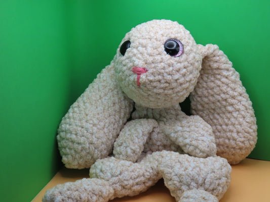 crochet bunny sitting on an orange table with a green background